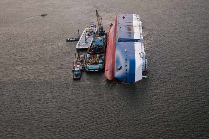 1540854386 featured image Capsized ship with cranes and tugboats around it