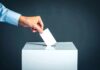 Hand placing ballot into voting box