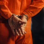 Person in orange jumpsuit with handcuffs behind back
