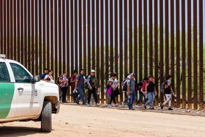2333258557 featured image People walking beside tall fence and border patrol vehicle