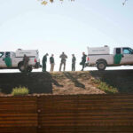 Border Patrol vehicles and agents on a ridge