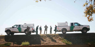 Border Patrol vehicles and agents on a ridge