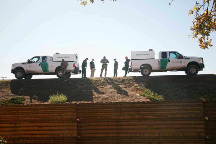 Border Patrol vehicles and agents on a ridge
