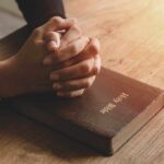 Hands praying on a Bible