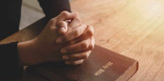 Hands praying on a Bible