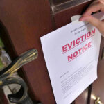 Hand tacking eviction notice on a wooden door