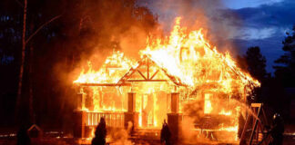 House engulfed in flames with firefighters present