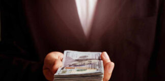 Hand holding a stack of hundred-dollar bills