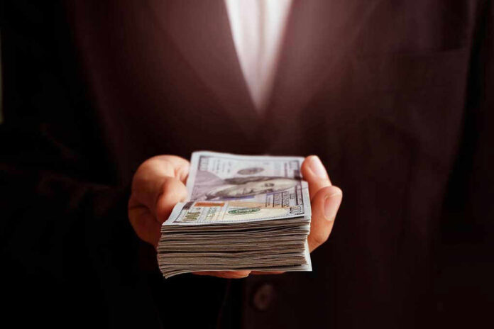 Hand holding a stack of hundred-dollar bills