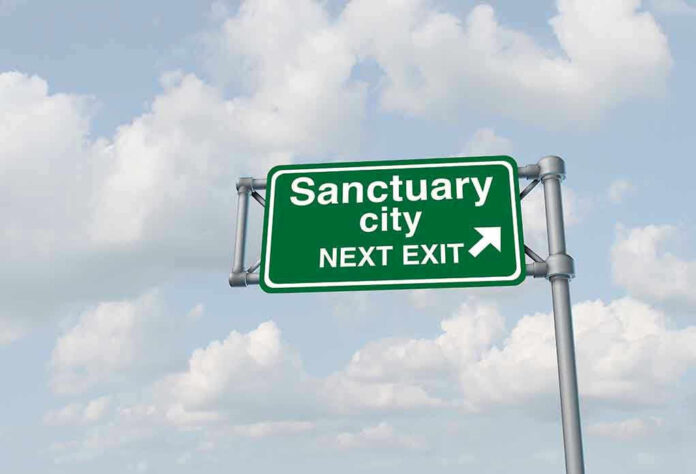 Green road sign saying sanctuary city next exit