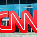 Large red CNN logo in front of a glass building