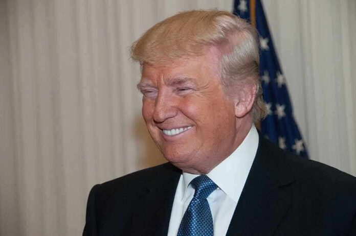 A smiling man in formal attire with an American flag in the background