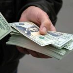 Argentina Bailout BACKLASH: Taxpayers Outrage! A hand holding a stack of hundred dollar bills with one bill prominently displayed