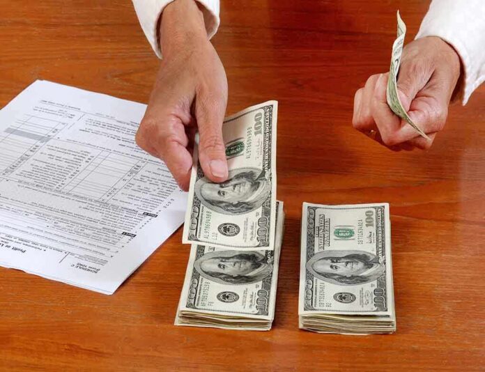 Hands counting cash and reviewing financial documents on a wooden table