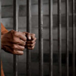 Illegal Immigrant Sentenced to THIRTY YEARS! Hands gripping prison cell bars