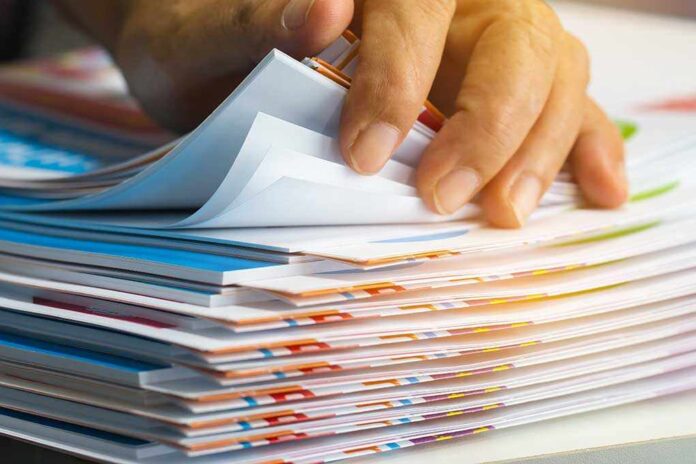 A hand flipping through a stack of colorful documents