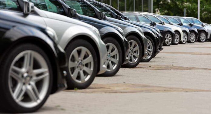 A row of parked black and silver cars in a dealership