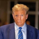 Factory Worker Confronts Trump–Does NOT END WELL Man in blue suit and striped tie, serious expression.