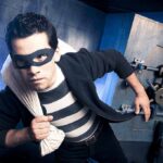 Shocking $200K Heist at Luxury Boutique A masked thief in a striped shirt holding a bag while emerging from a bank vault