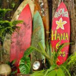 Colorful surfboards leaning against a tree in a tropical setting