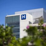 Modern hospital building with a prominent H sign against a clear blue sky