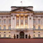 Front view of Buckingham Palace with illuminated facade and British flag
