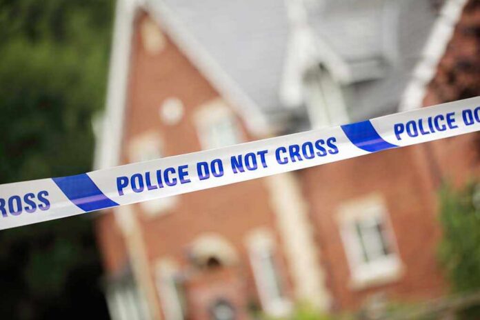 Police tape reading POLICE DO NOT CROSS in front of a house