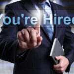 Businessman pointing at a digital display that says You're Hired