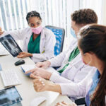 Shocking Diagnosis Hits Trump’s Inner Circle Doctors discussing chest X-ray results at a workstation.
