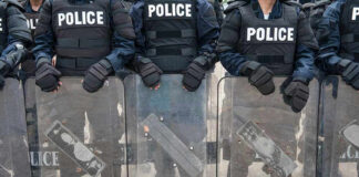 Police officers in riot gear holding shields.