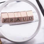 Fraud blocks under magnifying glass on invoices.