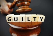 A gavel striking down next to wooden blocks spelling GUILTY