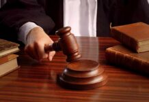 Wellness Guru’s Cult SLAMMED—9 Years! A judges hand holding a gavel over a wooden desk with law books