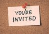 A note pinned to a corkboard that says 'YOU'RE INVITED'