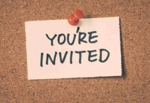 A note pinned to a corkboard that says 'YOU'RE INVITED'