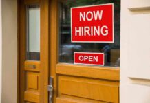 A door with a Now Hiring sign and an Open sign