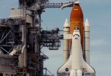 Space shuttle on launch pad with support structure.