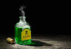 Cyanide War: China’s Brutal Tactic Uncovered Green poison bottle with cork on wooden surface.