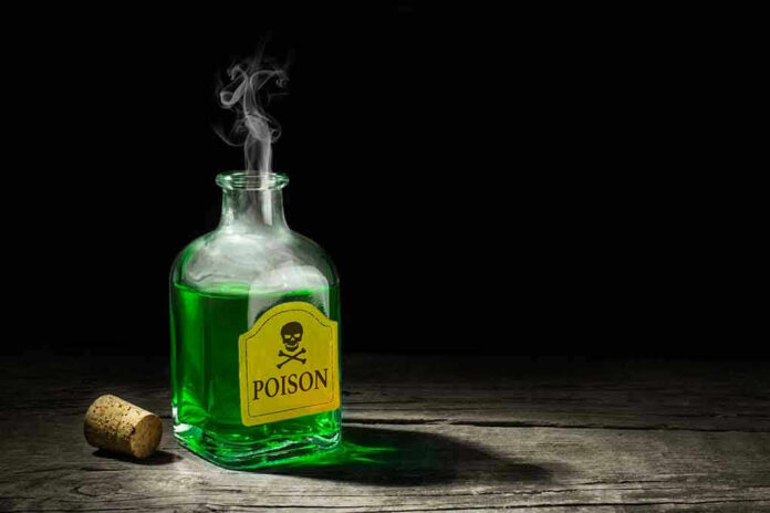 720129613 Green poison bottle with cork on wooden surface.