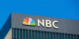 NBC logo displayed on a corporate building against a blue sky