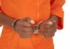 Hands of a person in handcuffs wearing an orange jumpsuit