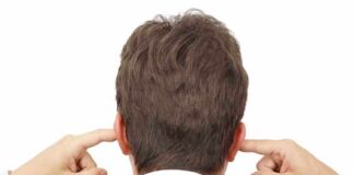 Man in a suit with his hands covering his ears, viewed from the back