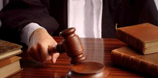 A judges hand holding a gavel over a wooden desk with law books