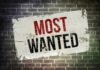 A weathered poster displaying the words MOST WANTED on a brick wall