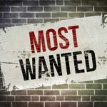 A weathered poster displaying the words MOST WANTED on a brick wall