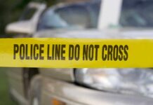 Yellow police tape reading POLICE LINE DO NOT CROSS in front of a vehicle