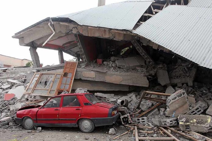 A red car parked next to a collapsed building with debris scattered around