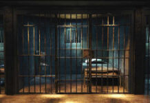 10 Men Dead in ICE Custody — Investigation Reveals Why Empty prison cell with metal bars and bed.