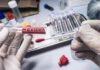 Gloved hands holding evidence swab in laboratory.