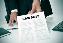 Person holding a document titled LAWSUIT in office.